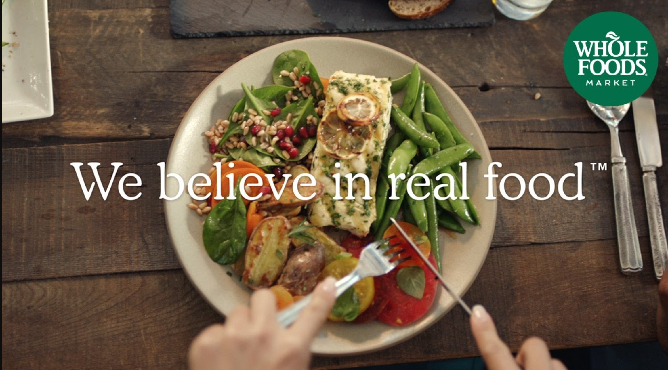 Whole Foods ad states "We believe in real food" and shows a plate full of healthy foods.